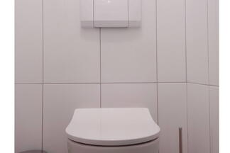 Weiße Toilette im weißgefliesten Bad