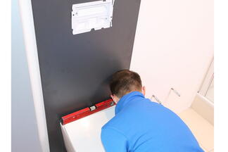 Monteur prüft Position des Washlets mit Wasserwaage